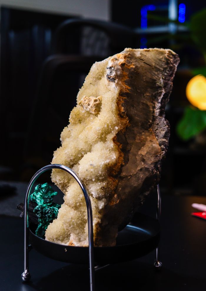 vision Close-up of a textured mineral rock on display indoors, showcasing detailed crystal formations.