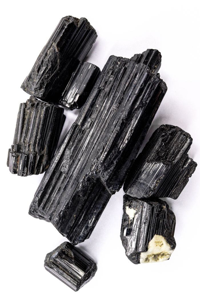 journey-02 Black tourmaline crystals arranged on a clean white surface, showcasing their natural texture and shine.