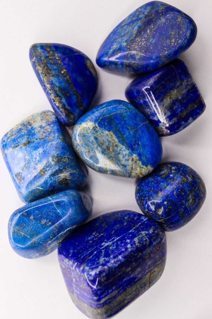 High-angle view of polished blue lapis lazuli stones on a white background.