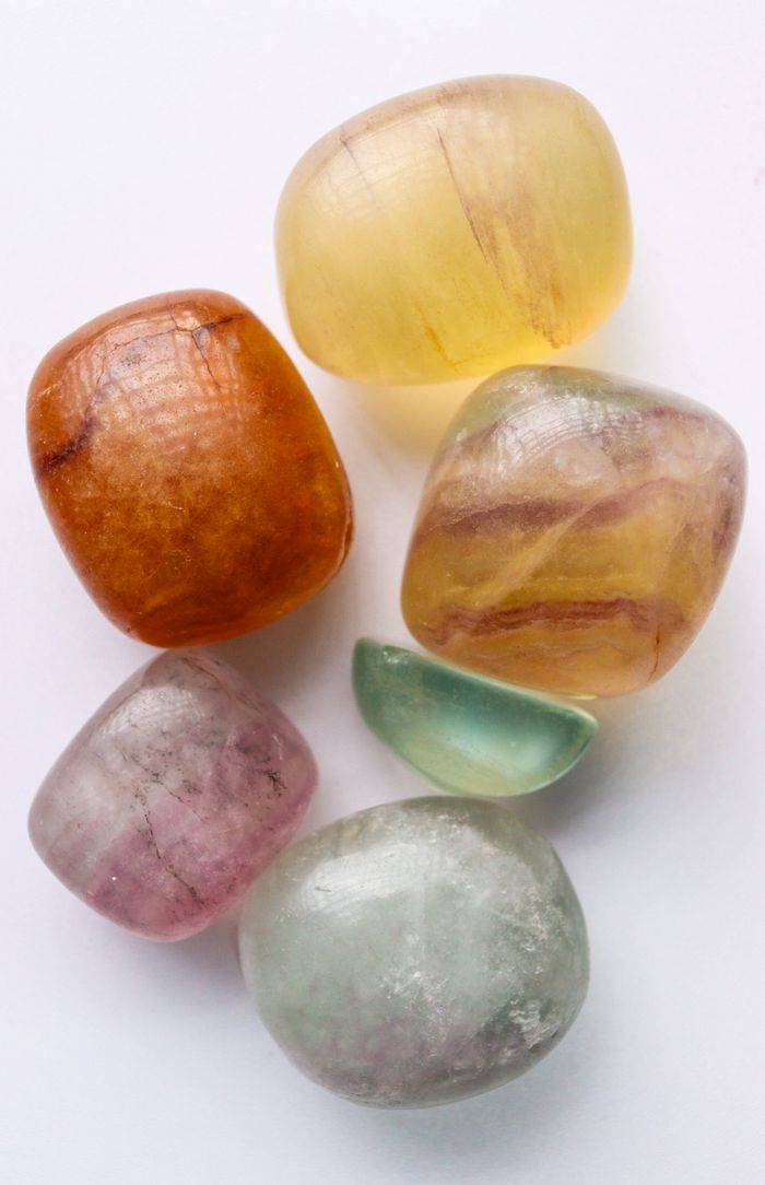 Close-up of various tumbled gemstones on a white background showcasing natural colors and textures.