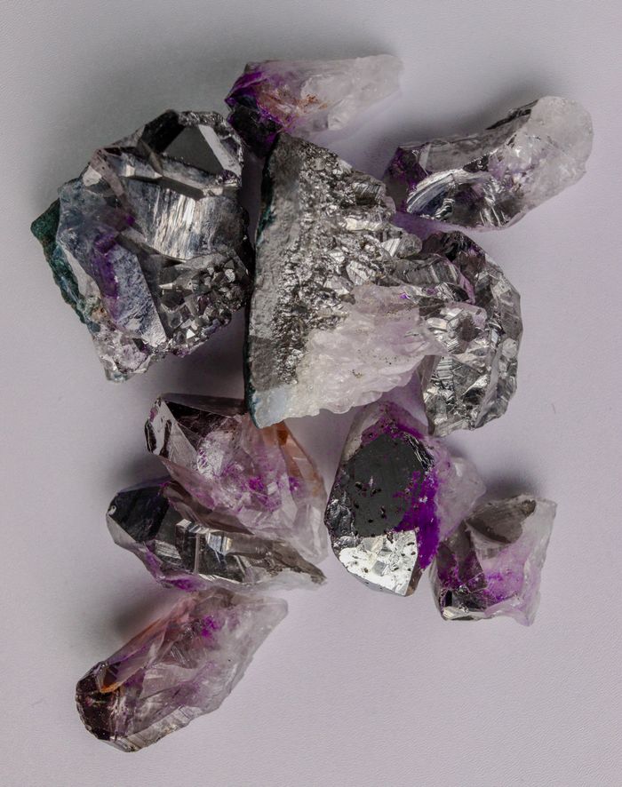 Close-up of amethyst and quartz mineral crystals showcasing vibrant purple hues against a neutral background.