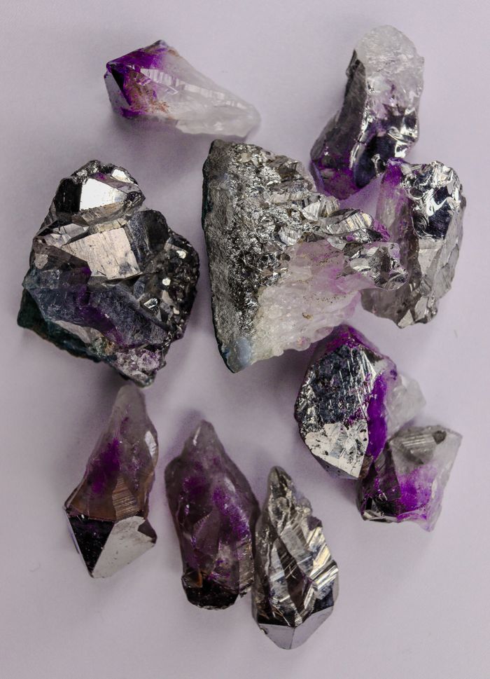 contact-img Detailed shot of amethyst crystals with pyrite inclusions on a neutral background.