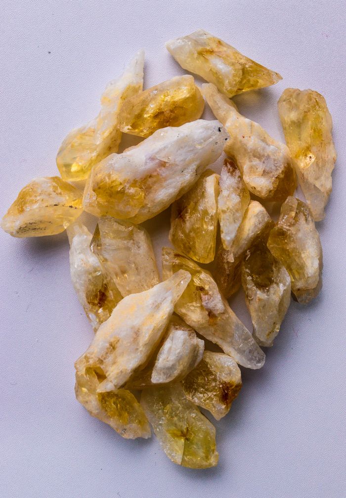about-img A collection of raw citrine quartz crystals on a white background, showcasing natural beauty and texture.