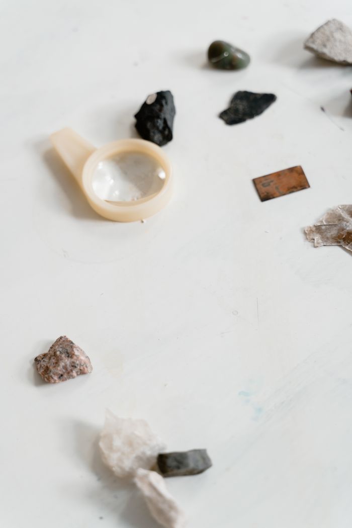 An assortment of rocks and a magnifying glass arranged on a white surface.